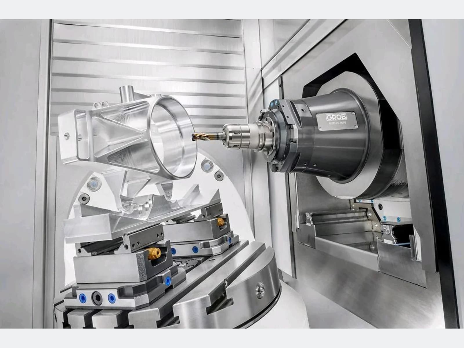 Five-axis CNC milling machine cutting an aluminum component inside the machining enclosure