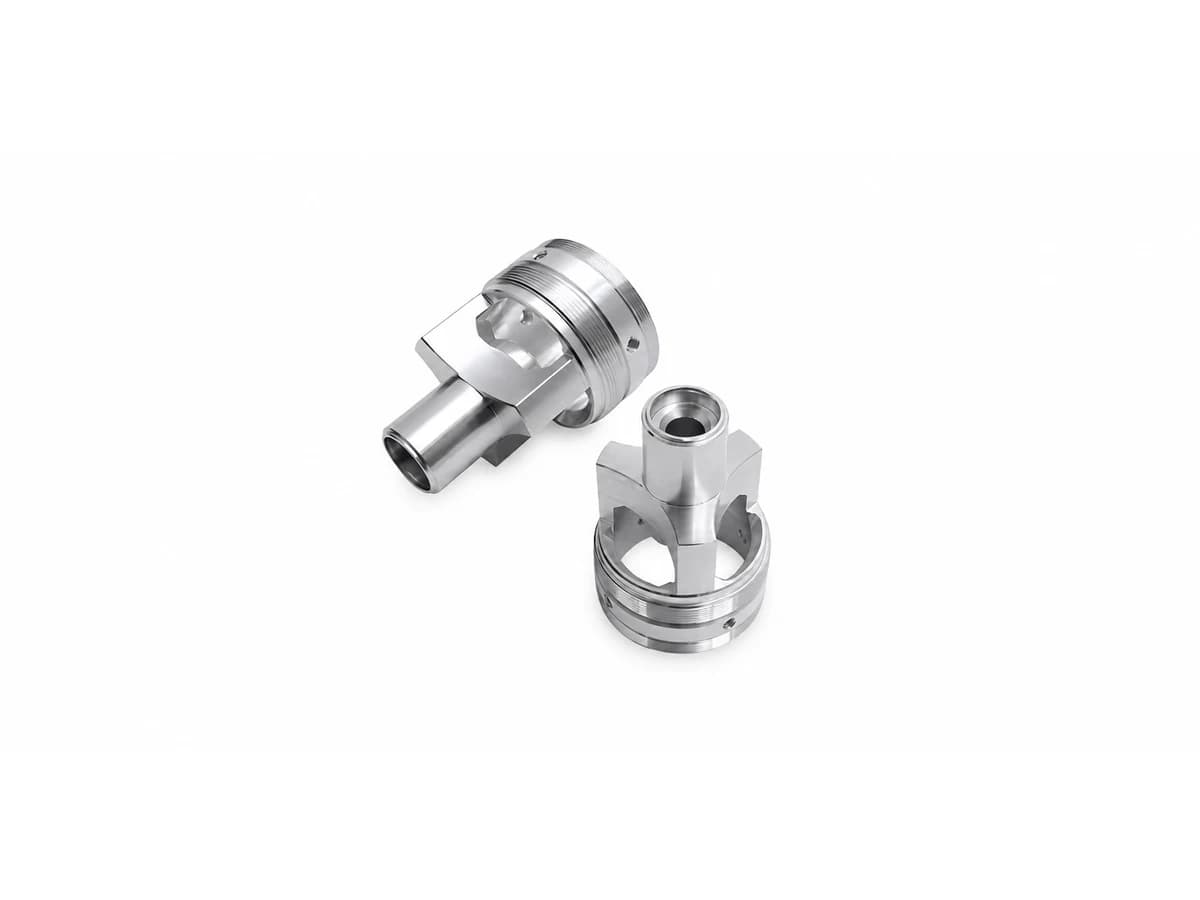 Complex precision CNC turned valve components with cross holes milled flats and internal bores on a pure white background