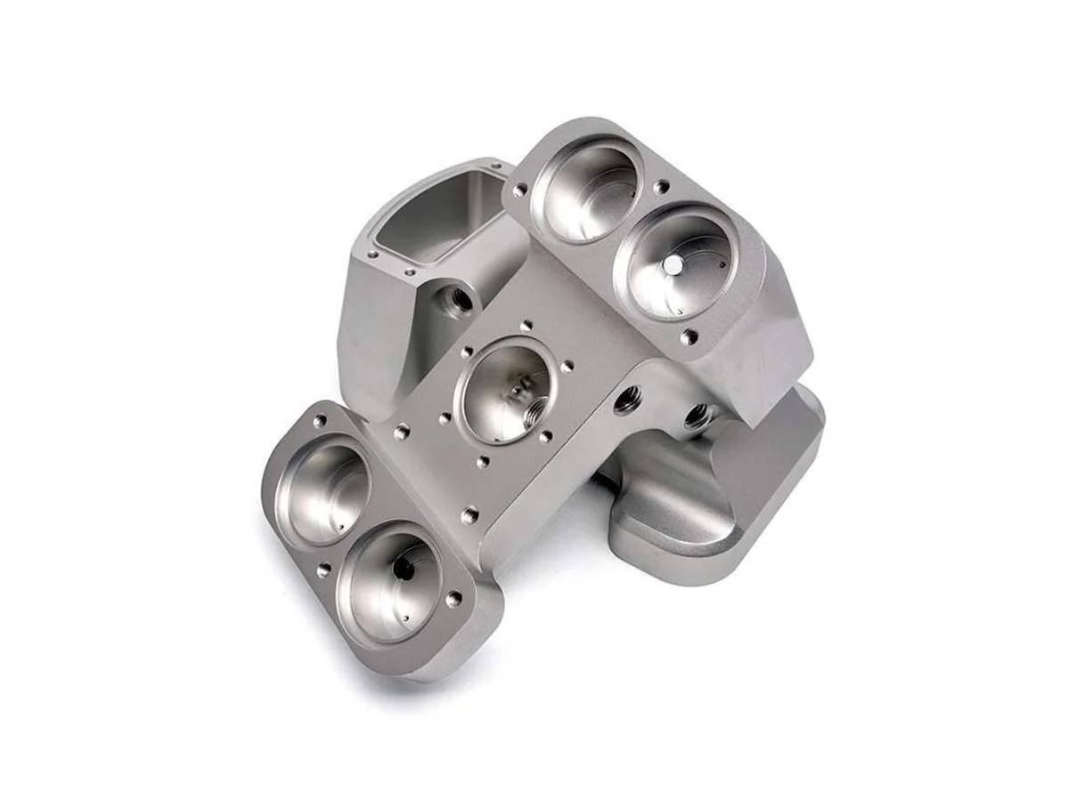 Complex 5-axis machined steel manifold with angled cavities ports and threaded holes on a white background