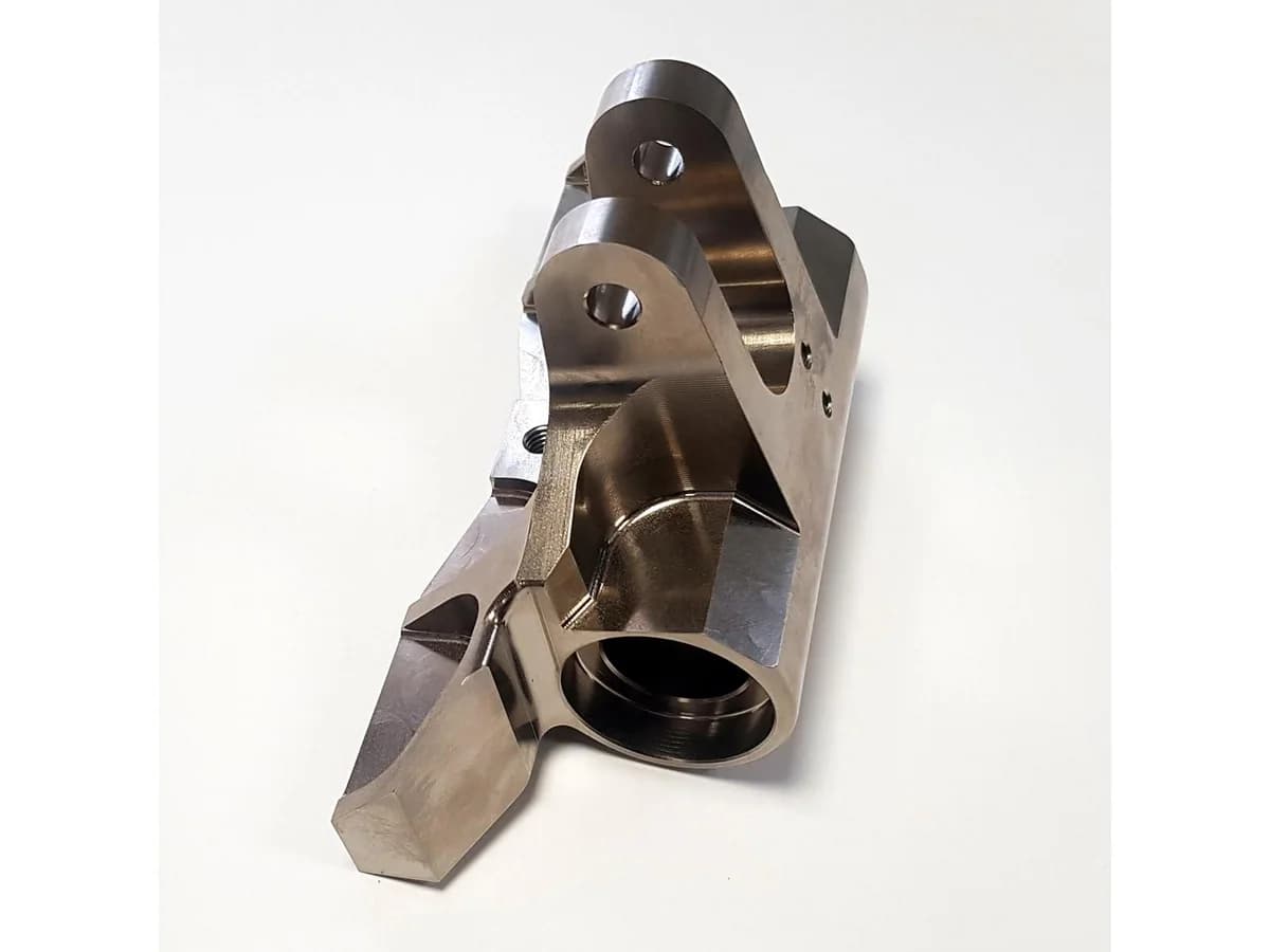 Custom 5-axis CNC machined steel bracket with deep pocket angled walls and precision mounting holes on a white background