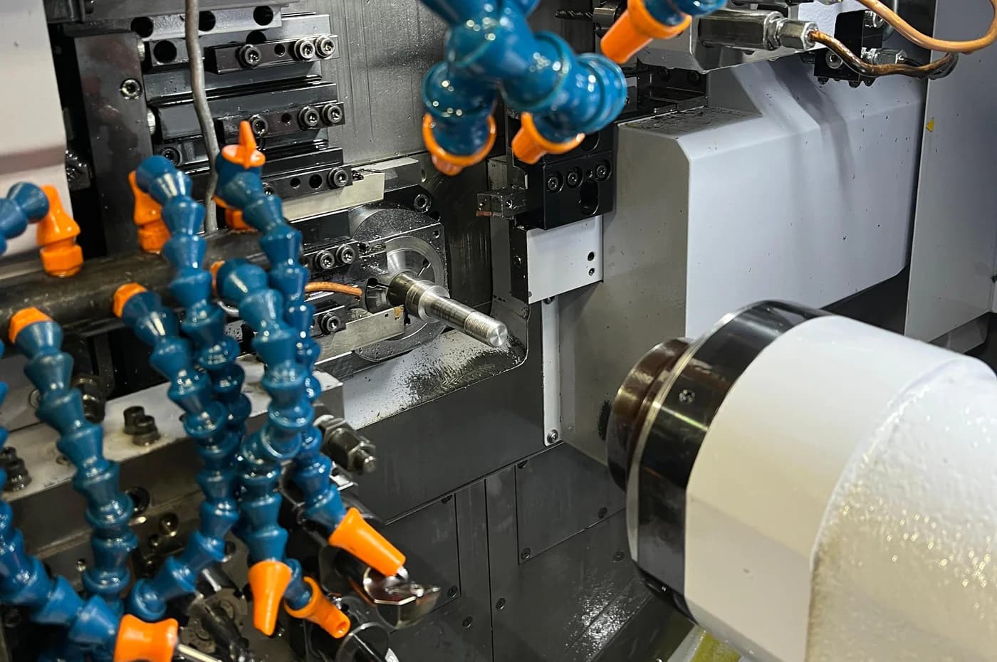 Swiss-type CNC lathe cutting small precision bar components with coolant and close tool access