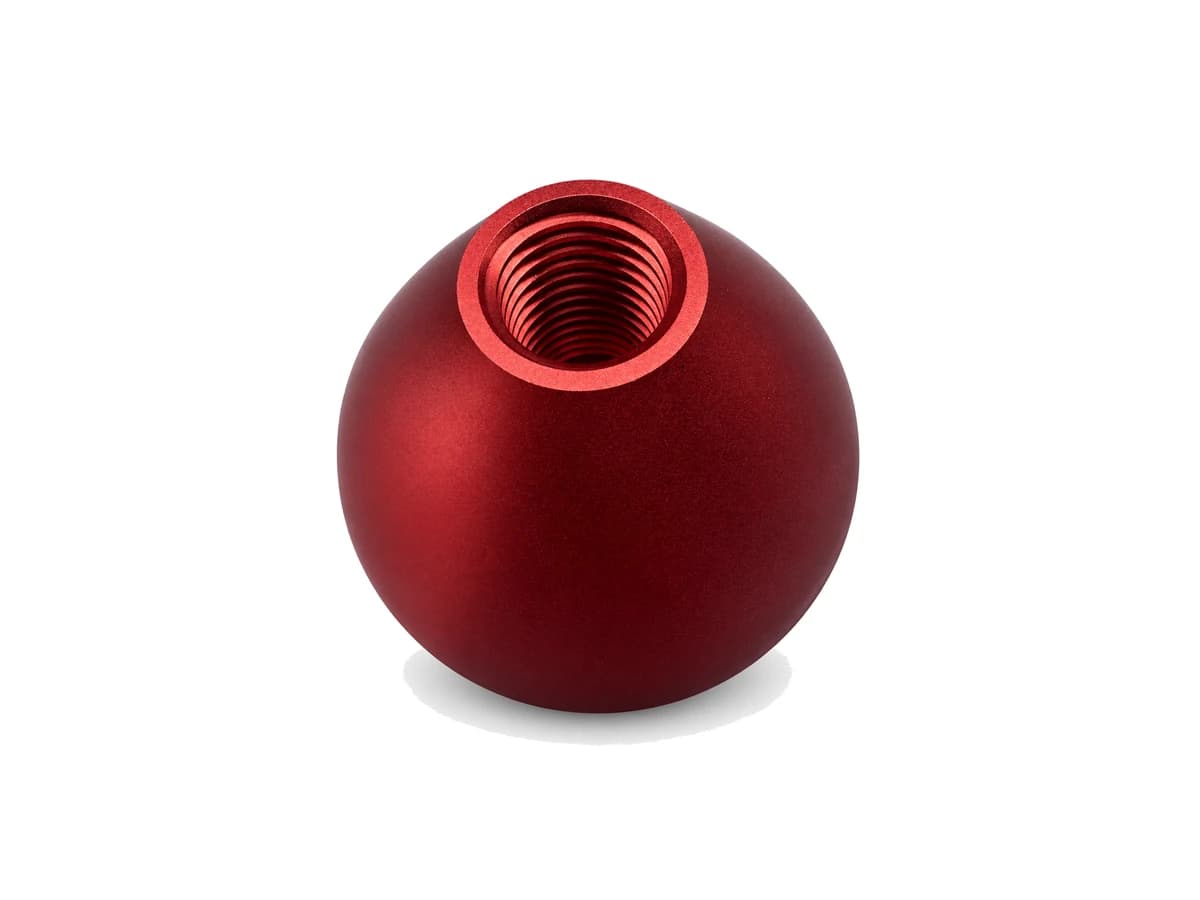 Red anodized spherical CNC machined aluminum component with threaded opening on a pure white background