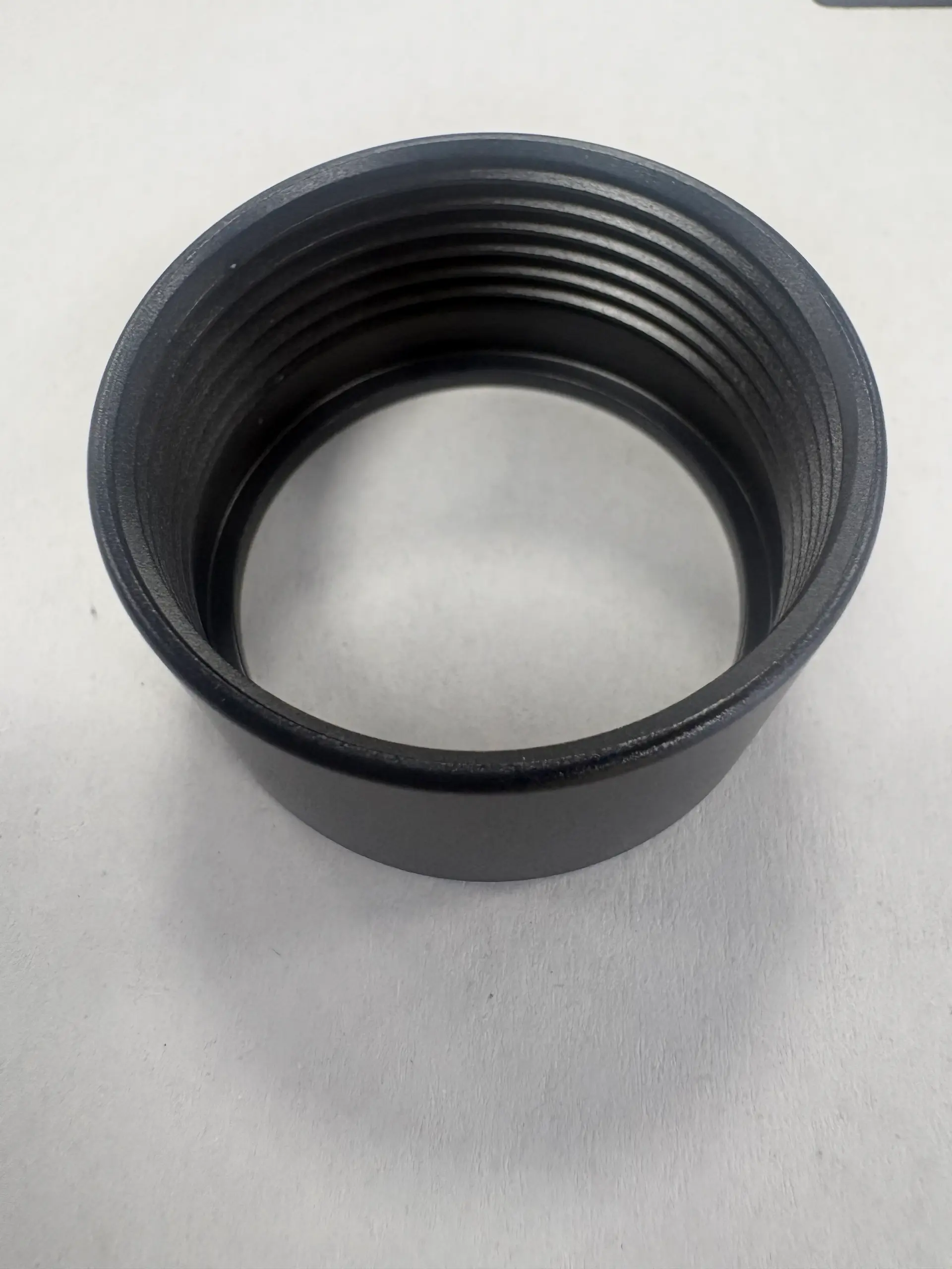 Black anodized aluminum threaded ring showing outer wall and internal grooves