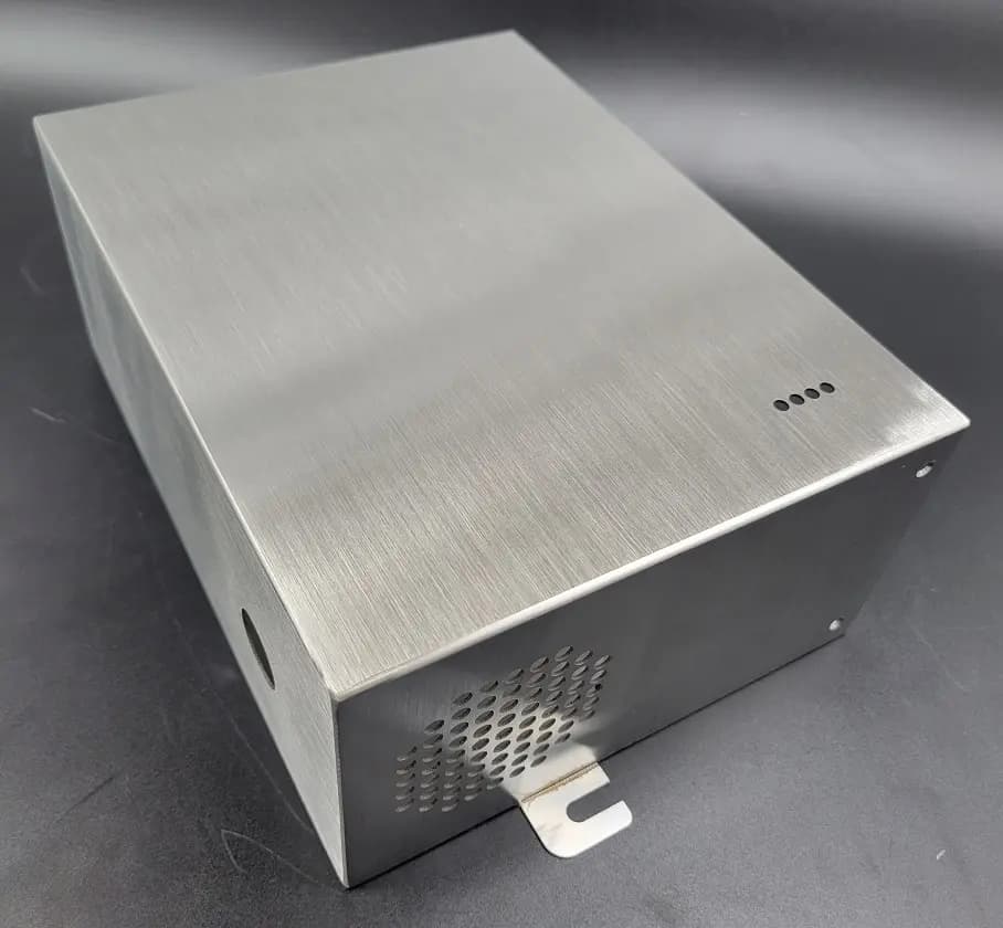 Brushed metal enclosure with directional grain and ventilation holes