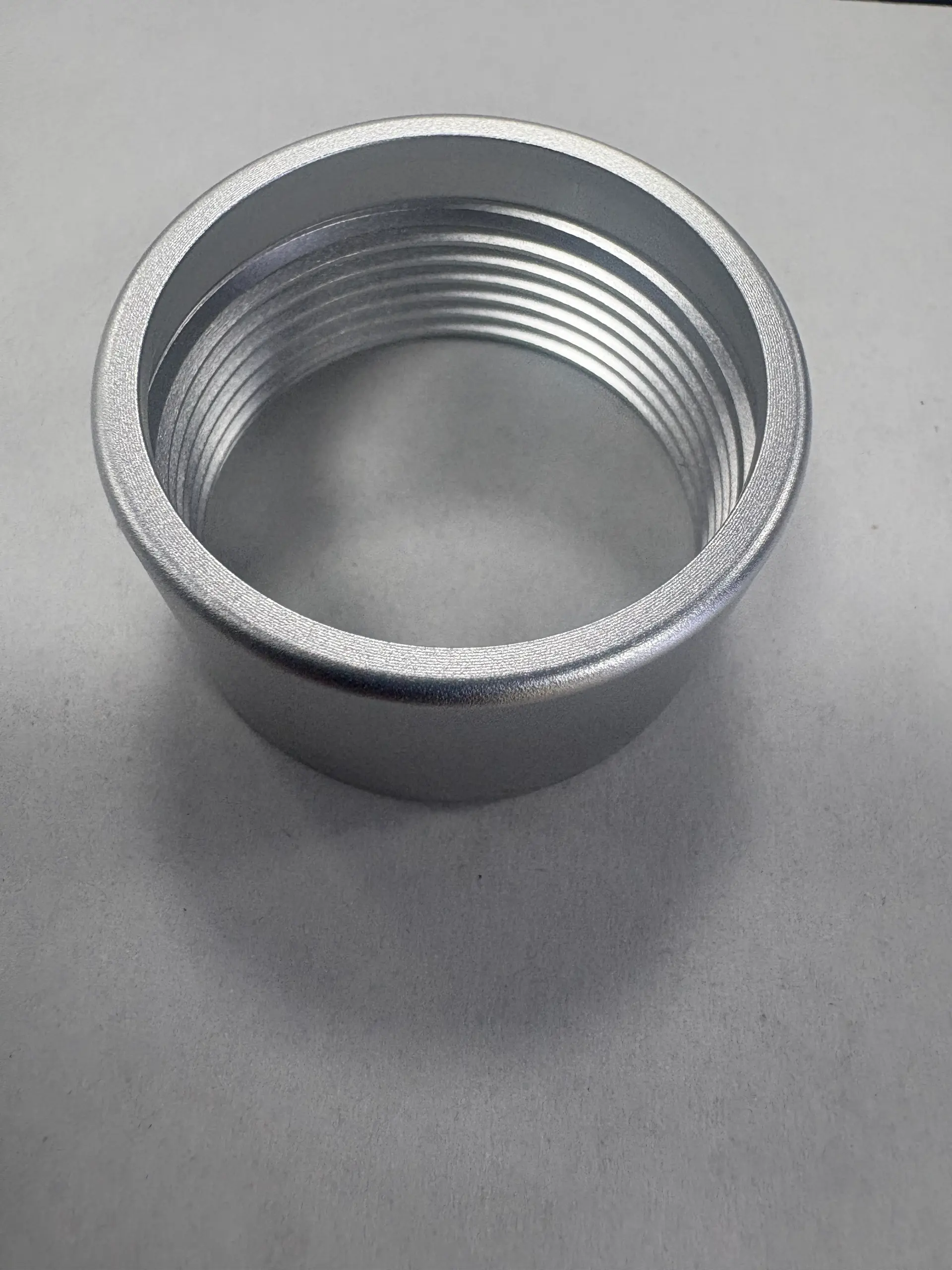 Clear silver anodized aluminum threaded ring showing metallic surface texture