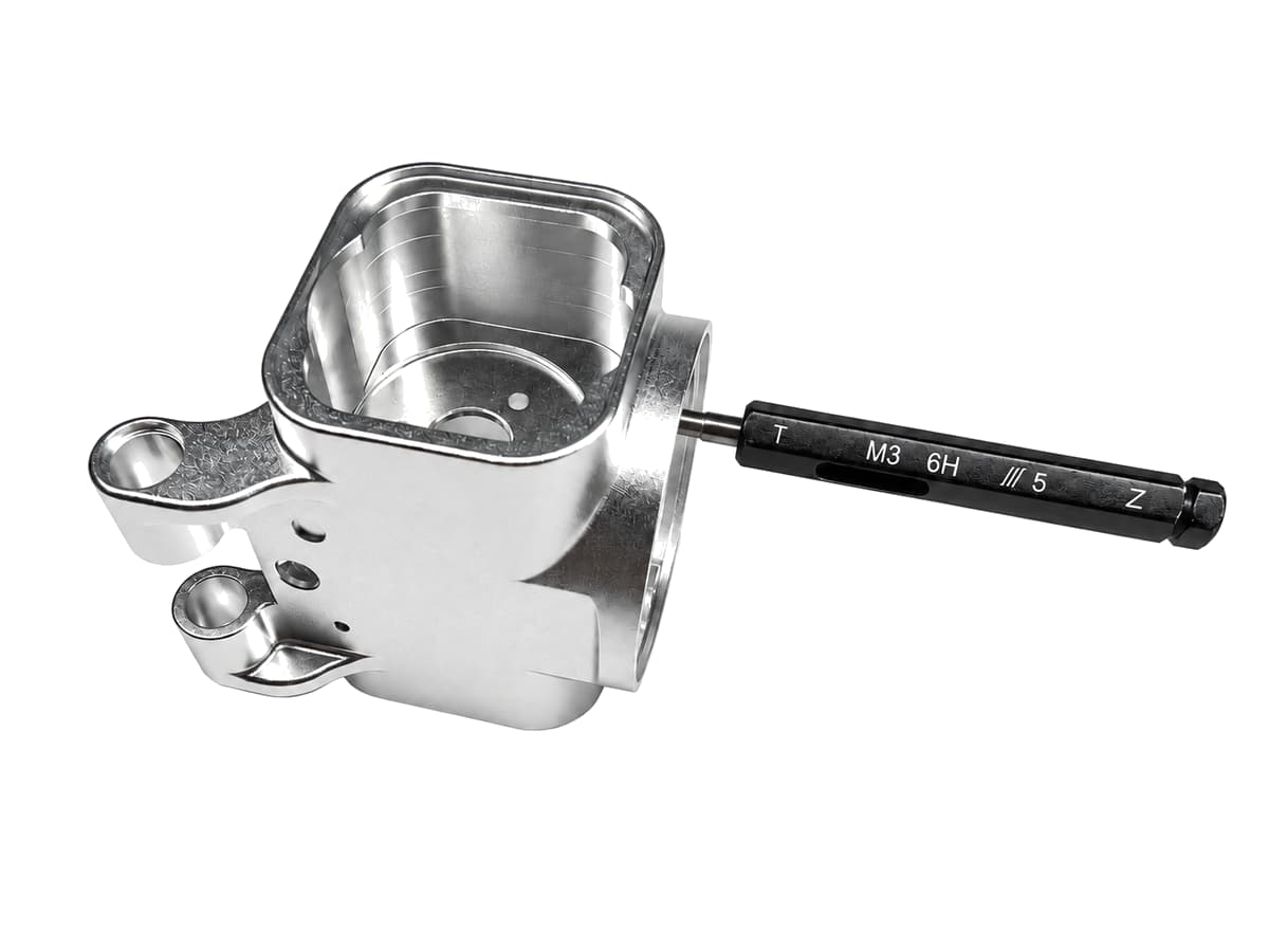 CNC machining thread gauge quality inspection on a precision machined housing with a pure white background