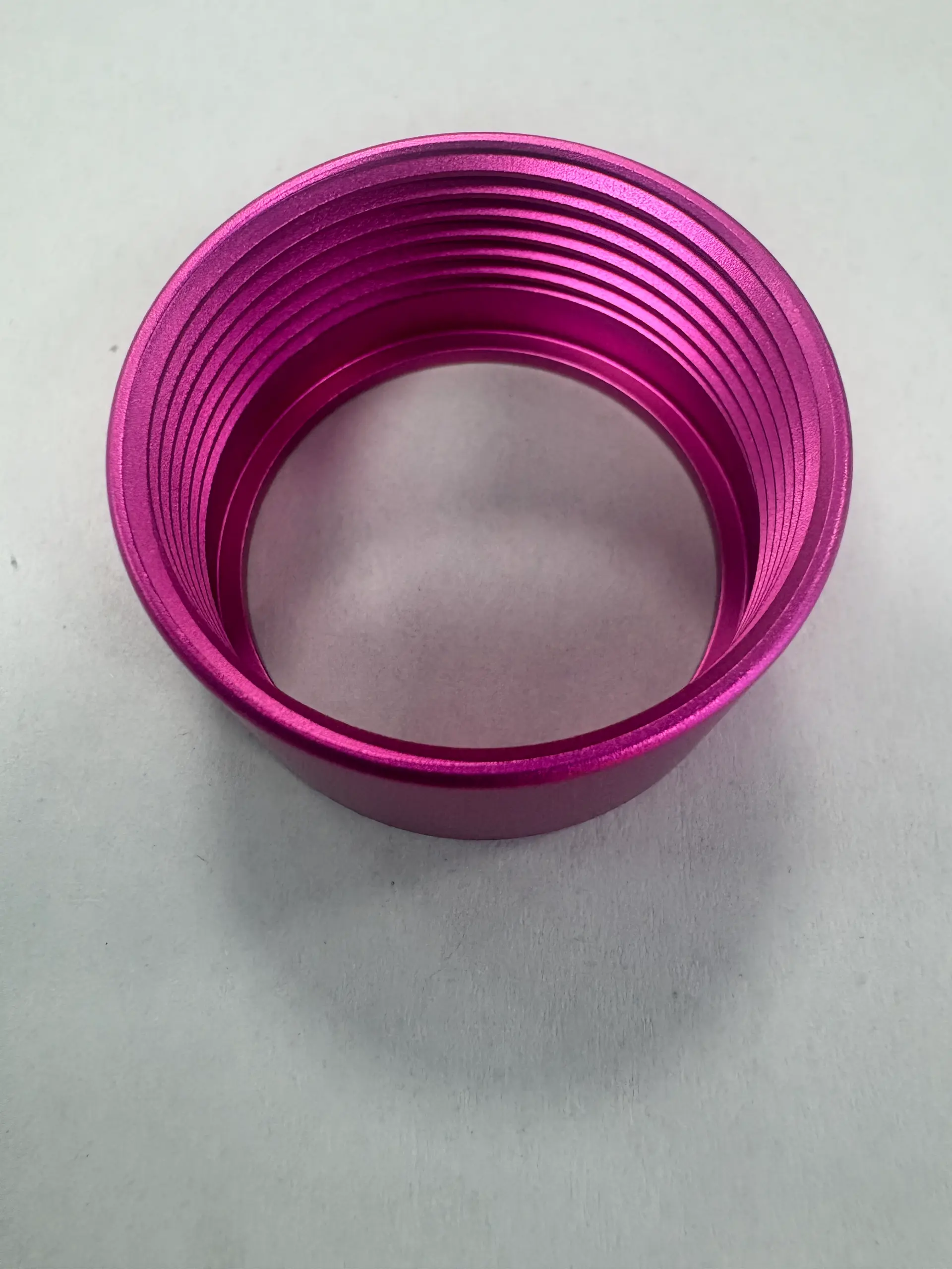 Bright pink anodized aluminum threaded ring with internal machined grooves