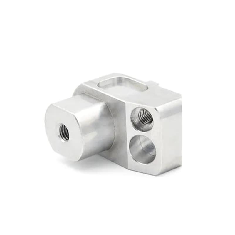 Small custom CNC machined silver connector with cross bores threaded holes and milled pocket on a pure white background