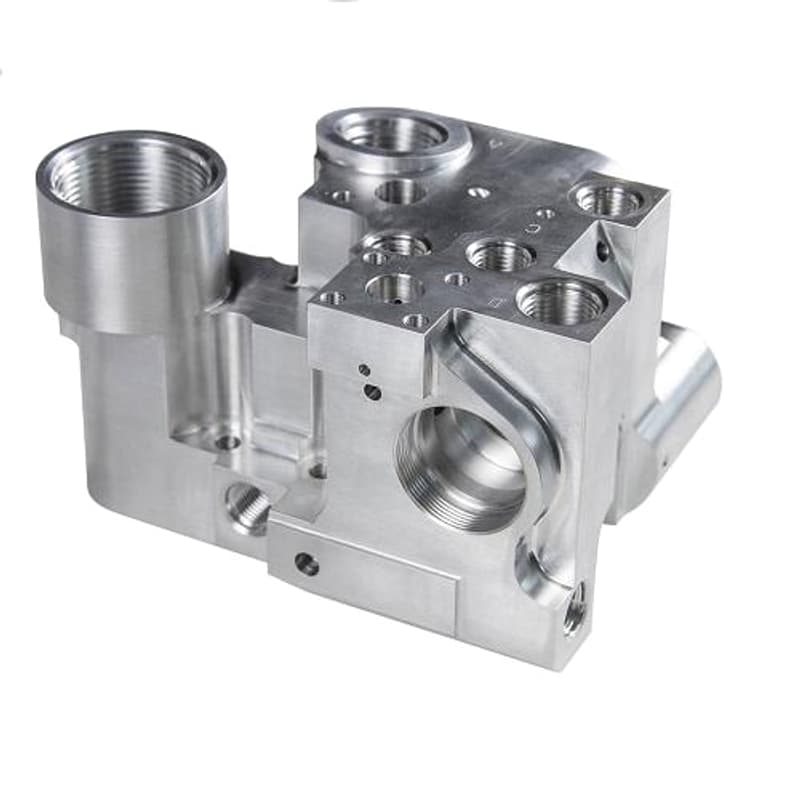 Precision machined silver manifold block with multiple threaded ports bores and interface faces on a pure white background