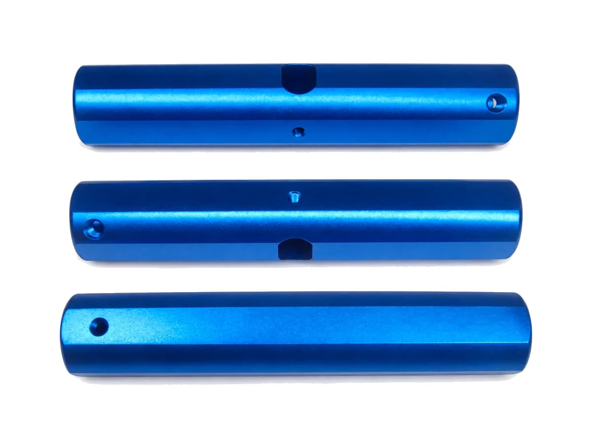 Three blue titanium alloy CNC machined medical component bodies on a pure white background